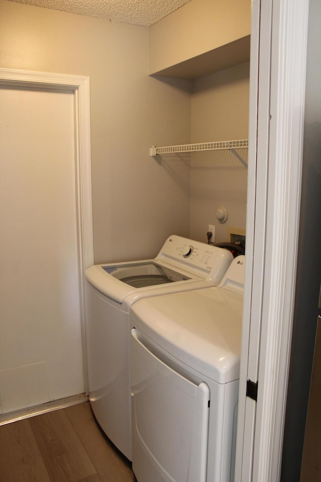 washroom with dark hardwood / wood-style flooring, washer and dryer, and a textured ceiling