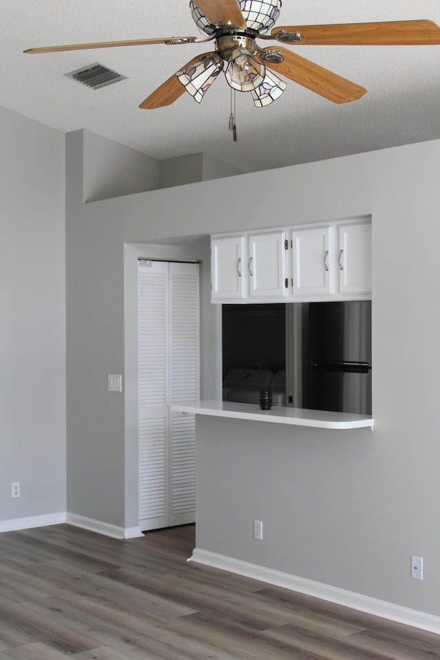 empty room featuring ceiling fan, dark wood-type flooring, and a textured ceiling