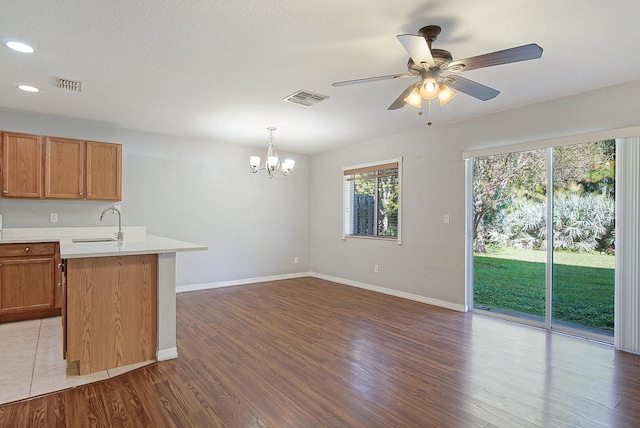 kitchen featuring ceiling fan with notable chandelier, dark hardwood / wood-style floors, hanging light fixtures, and sink