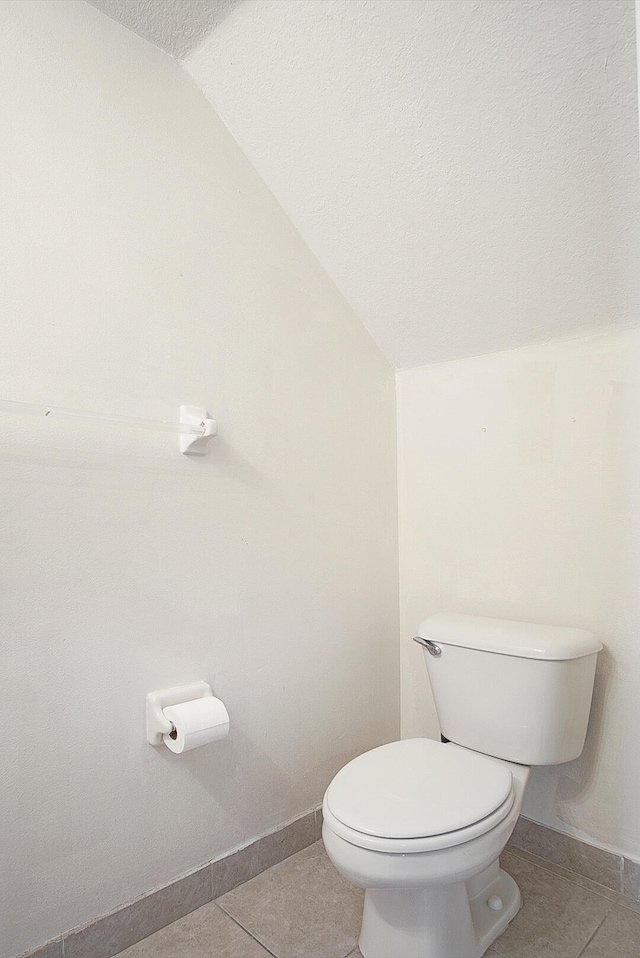 bathroom featuring tile patterned floors, toilet, lofted ceiling, and a textured ceiling