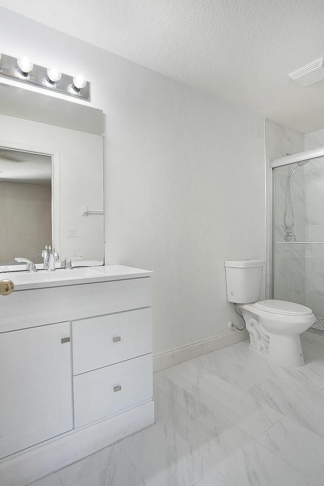 bathroom featuring vanity, toilet, a shower with shower door, and a textured ceiling