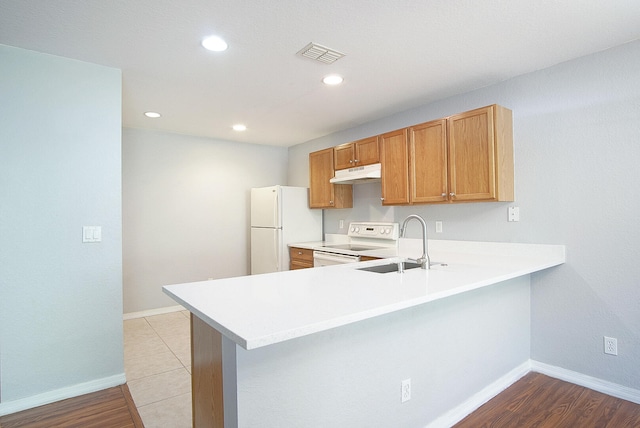 kitchen with kitchen peninsula, white appliances, light hardwood / wood-style floors, and sink