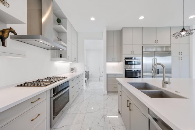 kitchen featuring sink, wall chimney range hood, hanging light fixtures, and appliances with stainless steel finishes