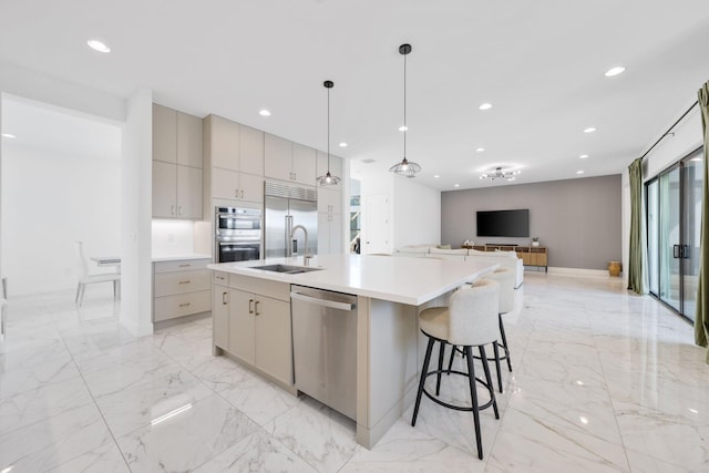 kitchen featuring stainless steel appliances, sink, hanging light fixtures, a breakfast bar area, and an island with sink