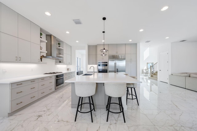 kitchen featuring sink, gray cabinets, appliances with stainless steel finishes, a large island, and a kitchen bar