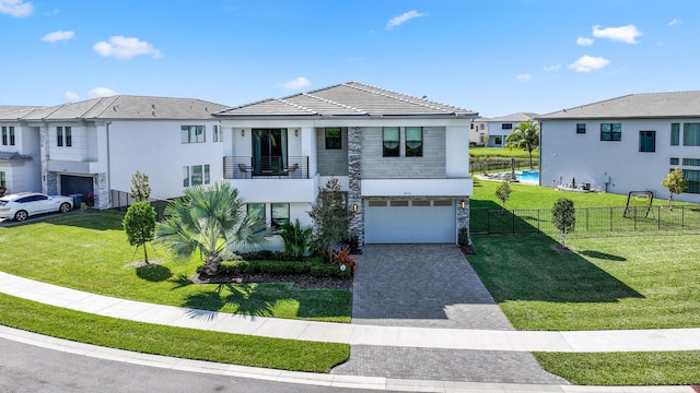 view of front of property featuring a balcony, a front yard, and a garage