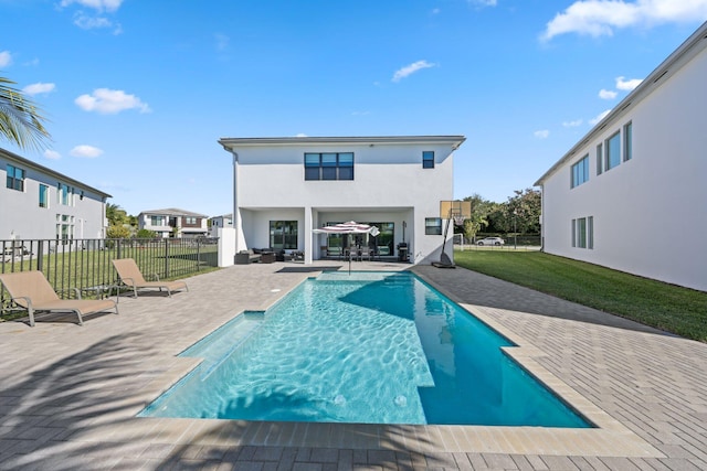 rear view of property with a fenced in pool, a patio area, and a lawn