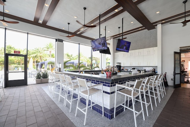 kitchen featuring a breakfast bar area, beamed ceiling, a towering ceiling, and pendant lighting