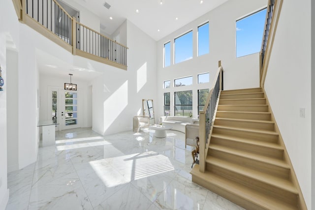 entryway featuring a towering ceiling, a wealth of natural light, and french doors