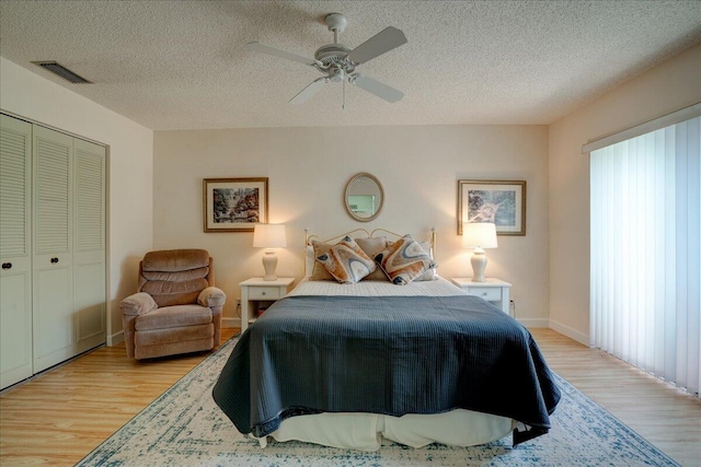 bedroom with ceiling fan, a closet, light hardwood / wood-style floors, and a textured ceiling