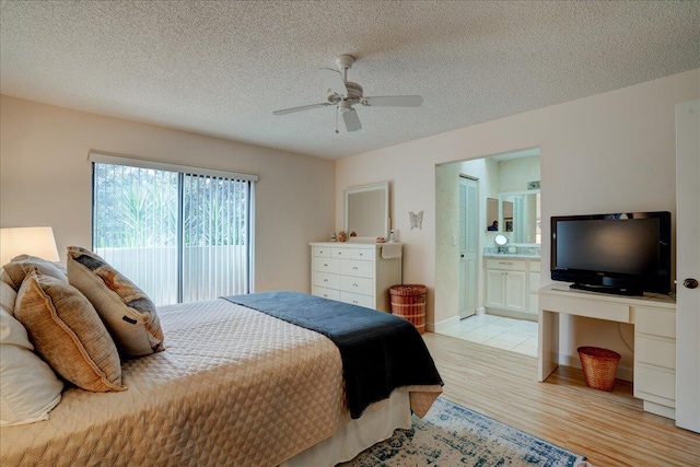 bedroom with ensuite bathroom, ceiling fan, light wood-type flooring, and a textured ceiling