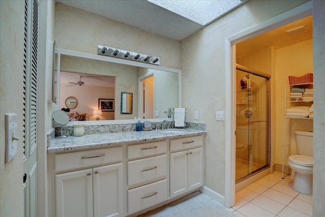 bathroom featuring vanity, tile patterned floors, ceiling fan, toilet, and an enclosed shower