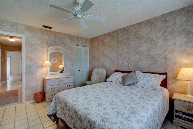 tiled bedroom with a textured ceiling, a closet, and ceiling fan