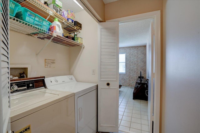 laundry room featuring light tile patterned floors, a textured ceiling, and washing machine and clothes dryer