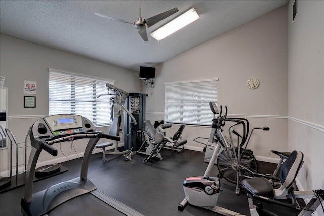 workout area with a textured ceiling, ceiling fan, and vaulted ceiling