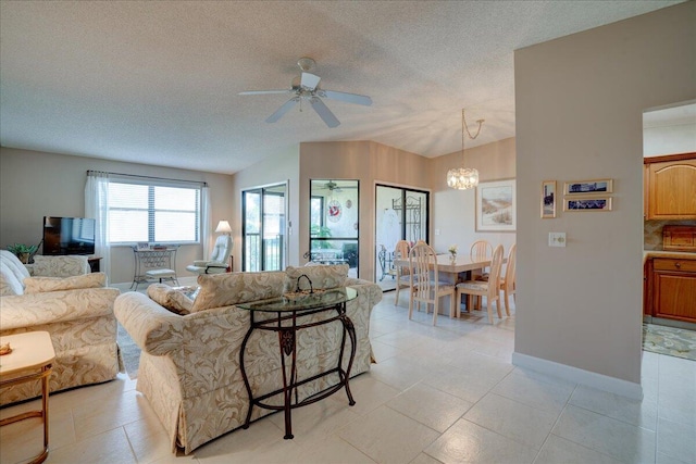 living room featuring ceiling fan with notable chandelier, light tile patterned floors, and a textured ceiling