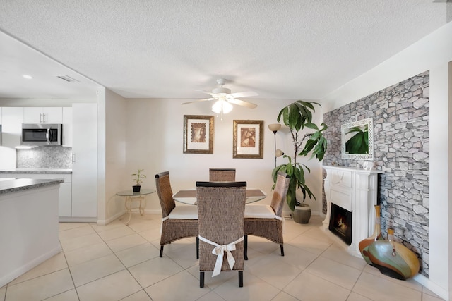 tiled dining room featuring a textured ceiling and ceiling fan