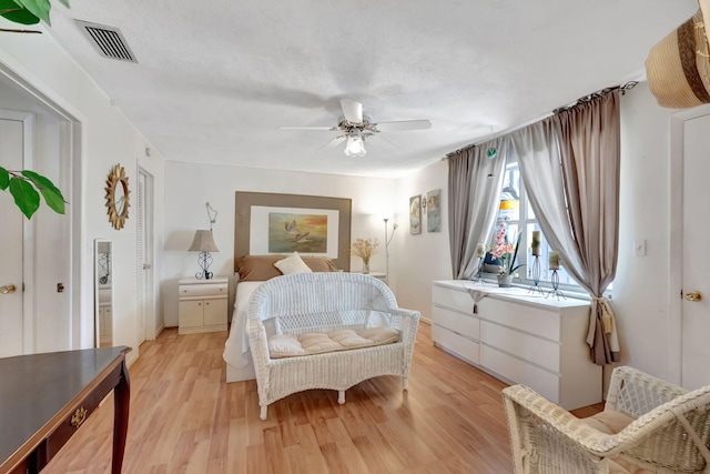 bedroom with a textured ceiling, light wood-type flooring, and ceiling fan