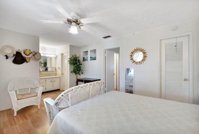 bedroom featuring ceiling fan, multiple closets, light wood-type flooring, and ensuite bath