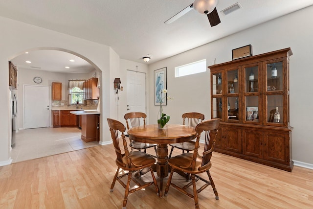 dining area with a textured ceiling, light wood-type flooring, ceiling fan, and a barn door