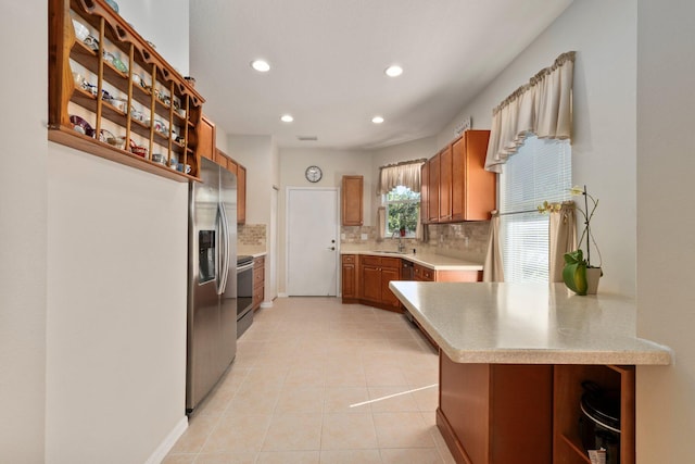 kitchen with sink, backsplash, kitchen peninsula, light tile patterned floors, and appliances with stainless steel finishes