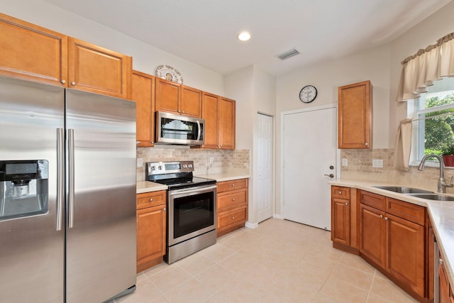 kitchen with decorative backsplash, stainless steel appliances, light tile patterned flooring, and sink