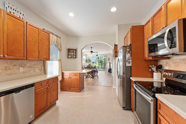 kitchen with appliances with stainless steel finishes, tasteful backsplash, light hardwood / wood-style flooring, and ceiling fan