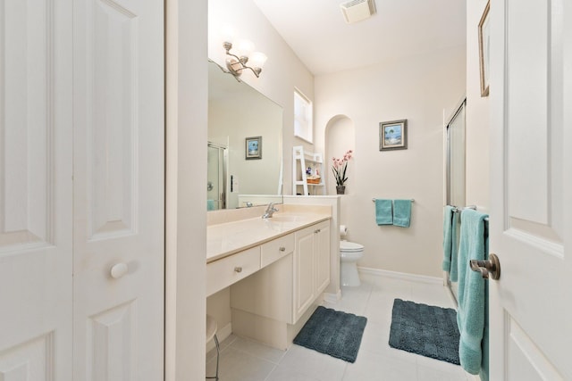 bathroom featuring tile patterned flooring, vanity, toilet, and a shower with door