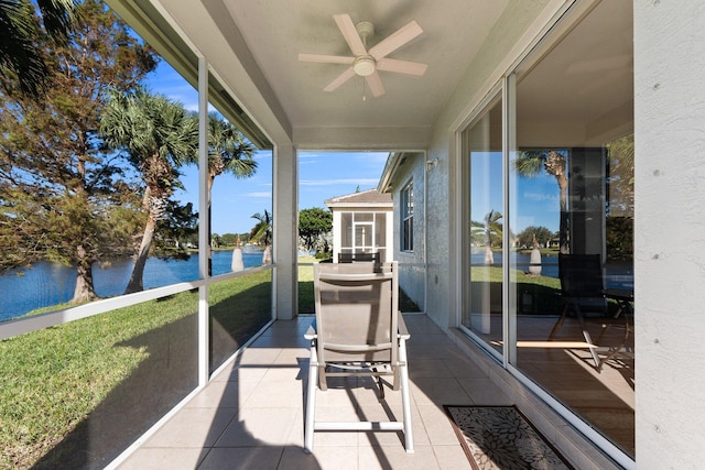 sunroom / solarium with ceiling fan and a water view