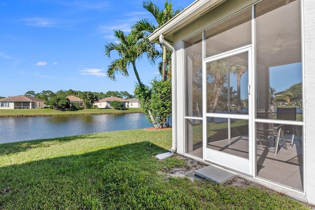 view of yard featuring a sunroom and a water view