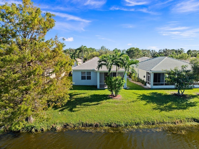 rear view of property featuring a lawn, a sunroom, and a water view