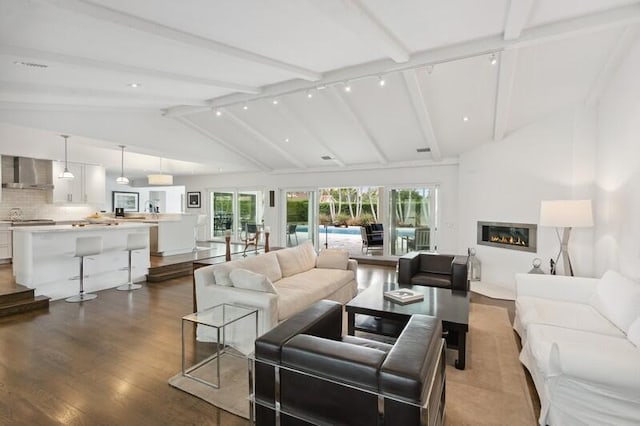 living room featuring hardwood / wood-style floors, track lighting, and vaulted ceiling with beams