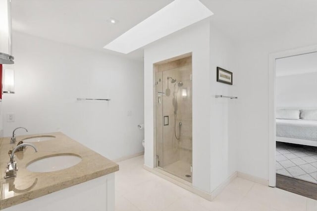 bathroom with toilet, vanity, tile patterned flooring, a shower with shower door, and a skylight