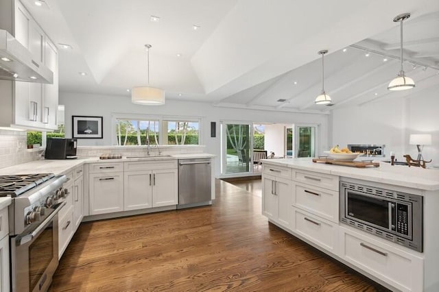 kitchen featuring vaulted ceiling, stainless steel appliances, white cabinets, and hanging light fixtures