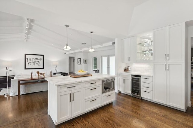 kitchen with stainless steel microwave, lofted ceiling with beams, beverage cooler, and white cabinetry