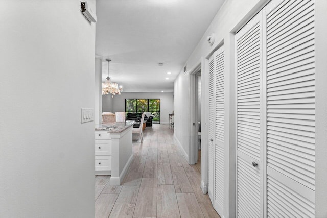 hallway with light wood-type flooring and a notable chandelier