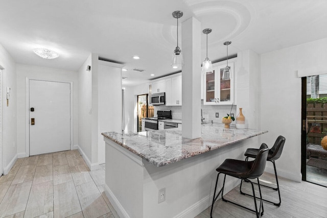 kitchen with electric stove, pendant lighting, white cabinets, and kitchen peninsula