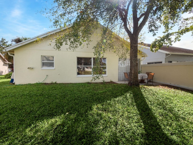 back of house with a lawn and a patio