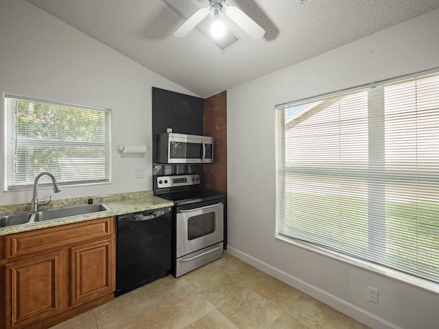 kitchen with lofted ceiling, sink, stainless steel appliances, and a textured ceiling