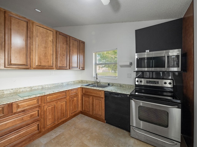 kitchen featuring sink, light stone countertops, a textured ceiling, and appliances with stainless steel finishes