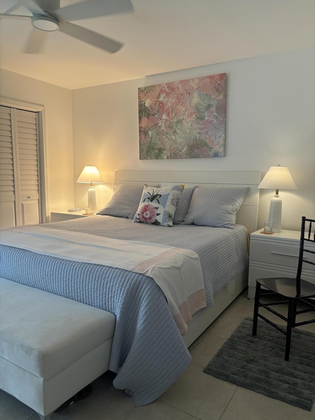 tiled bedroom with ceiling fan and a closet