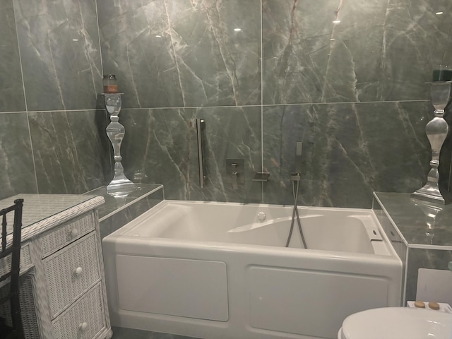 bathroom with a bath, toilet, and tile walls