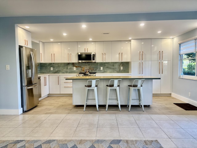 kitchen featuring backsplash, a breakfast bar, white cabinetry, and stainless steel appliances