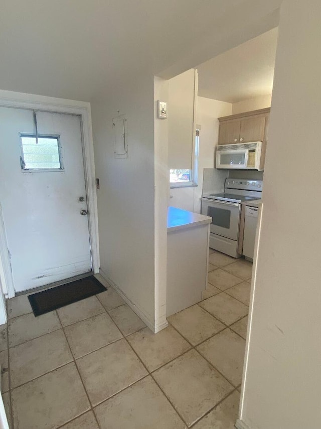 kitchen featuring white appliances, light tile patterned floors, and light countertops