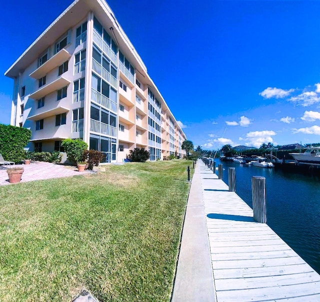 view of dock with a water view and a lawn