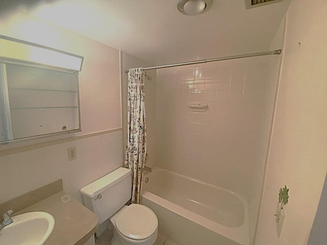 bathroom featuring toilet, a wainscoted wall, shower / tub combo, vanity, and tile walls