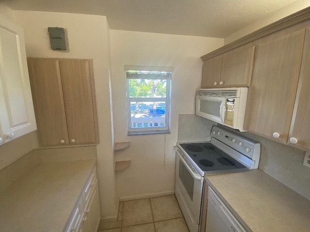 kitchen featuring light tile patterned floors, light countertops, white appliances, and baseboards