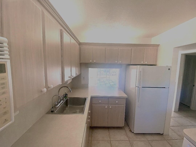 kitchen featuring light tile patterned floors, freestanding refrigerator, light countertops, a textured ceiling, and a sink