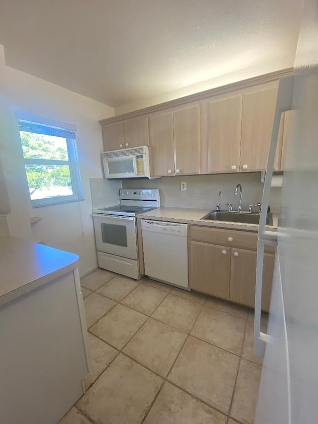 kitchen featuring white appliances, light tile patterned floors, light countertops, and a sink