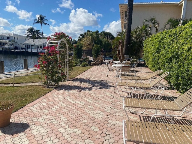 view of patio with a water view and fence